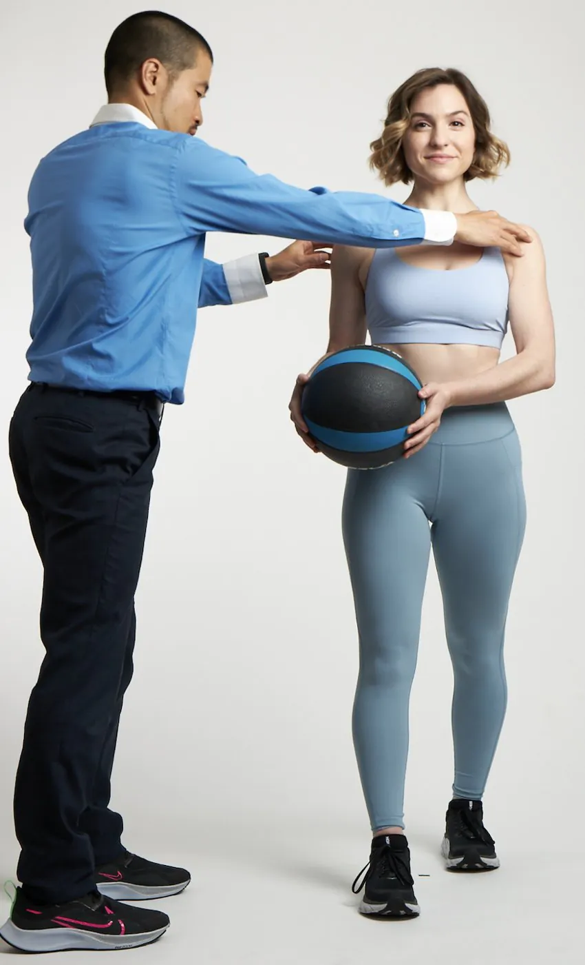 medicine-ball-shoulder-check-nyc TAI NYCで、院長の仲野広倫がメディシンボールを持つ患者の肩の位置を確かめている様子